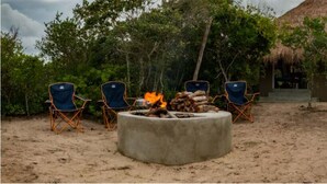 A sandy outdoor area with a concrete fire pit surrounded by four blue folding chairs. - Maqueda @ Mozambique (Manhica)