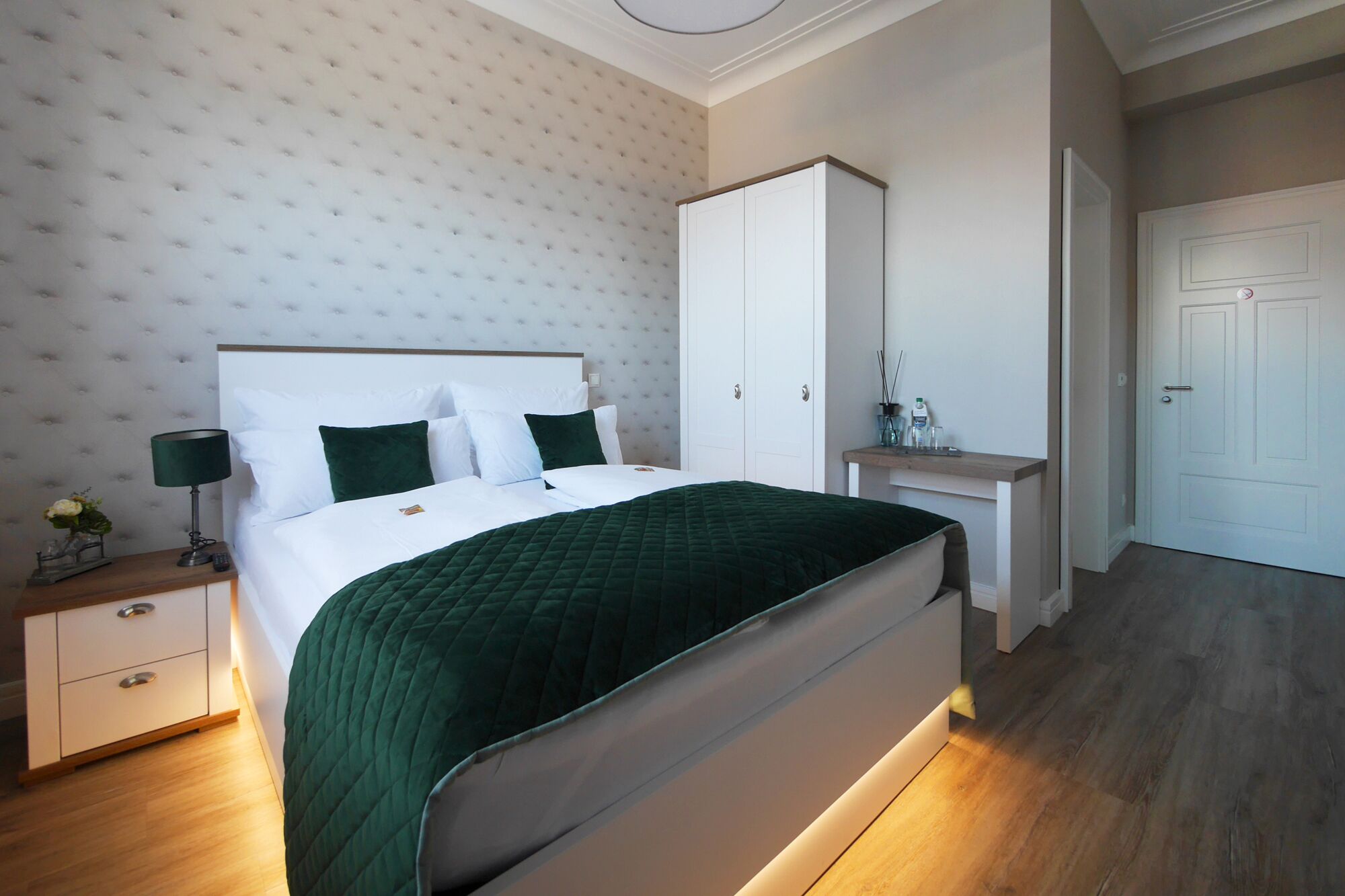 Ein ordentlich eingerichtetes Schlafzimmer mit Bett, Nachttisch, Lampe und Kleiderschrank.