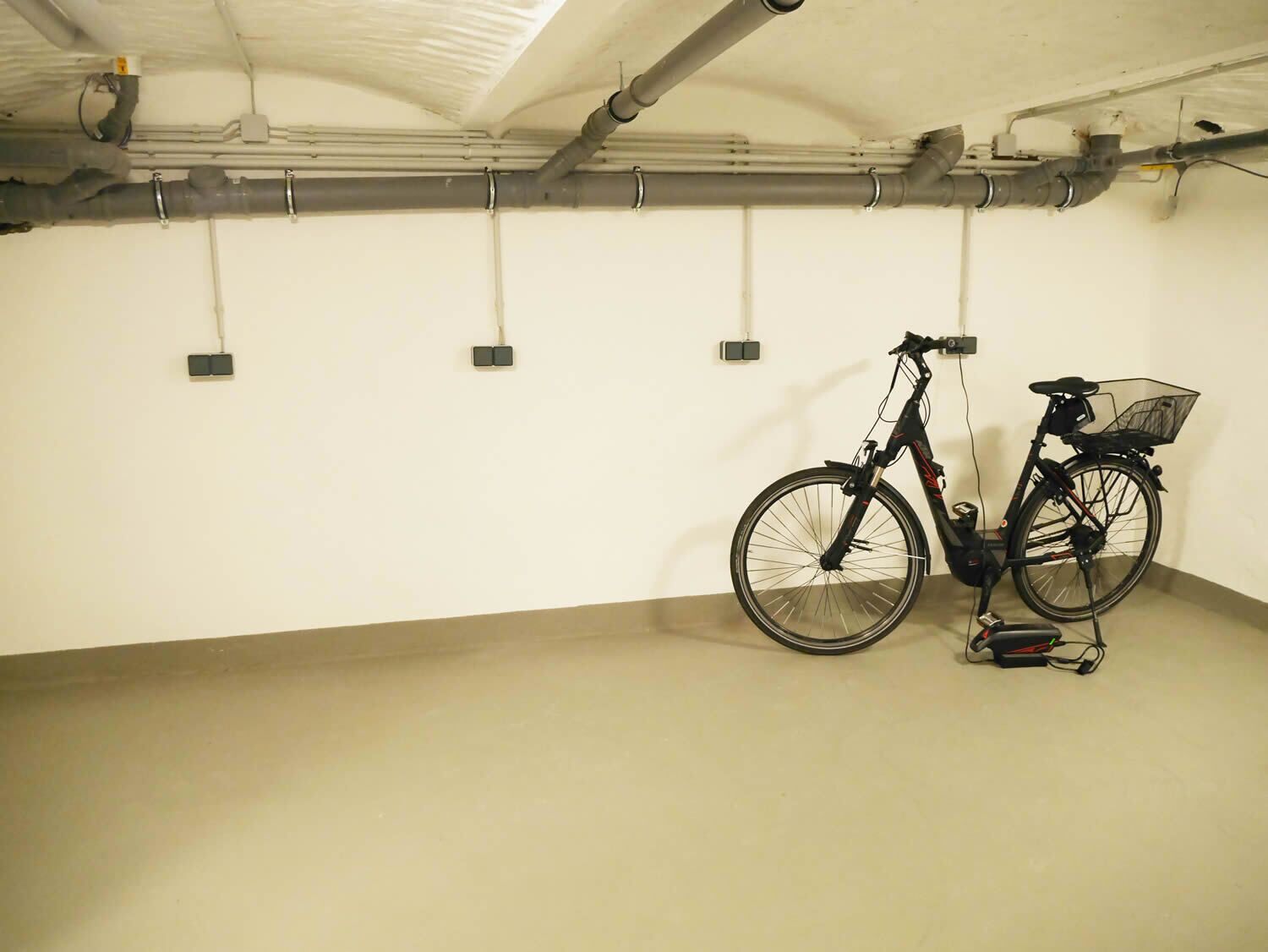 Un estacionamiento limpio y vacío, con una bicicleta apoyada en la pared.