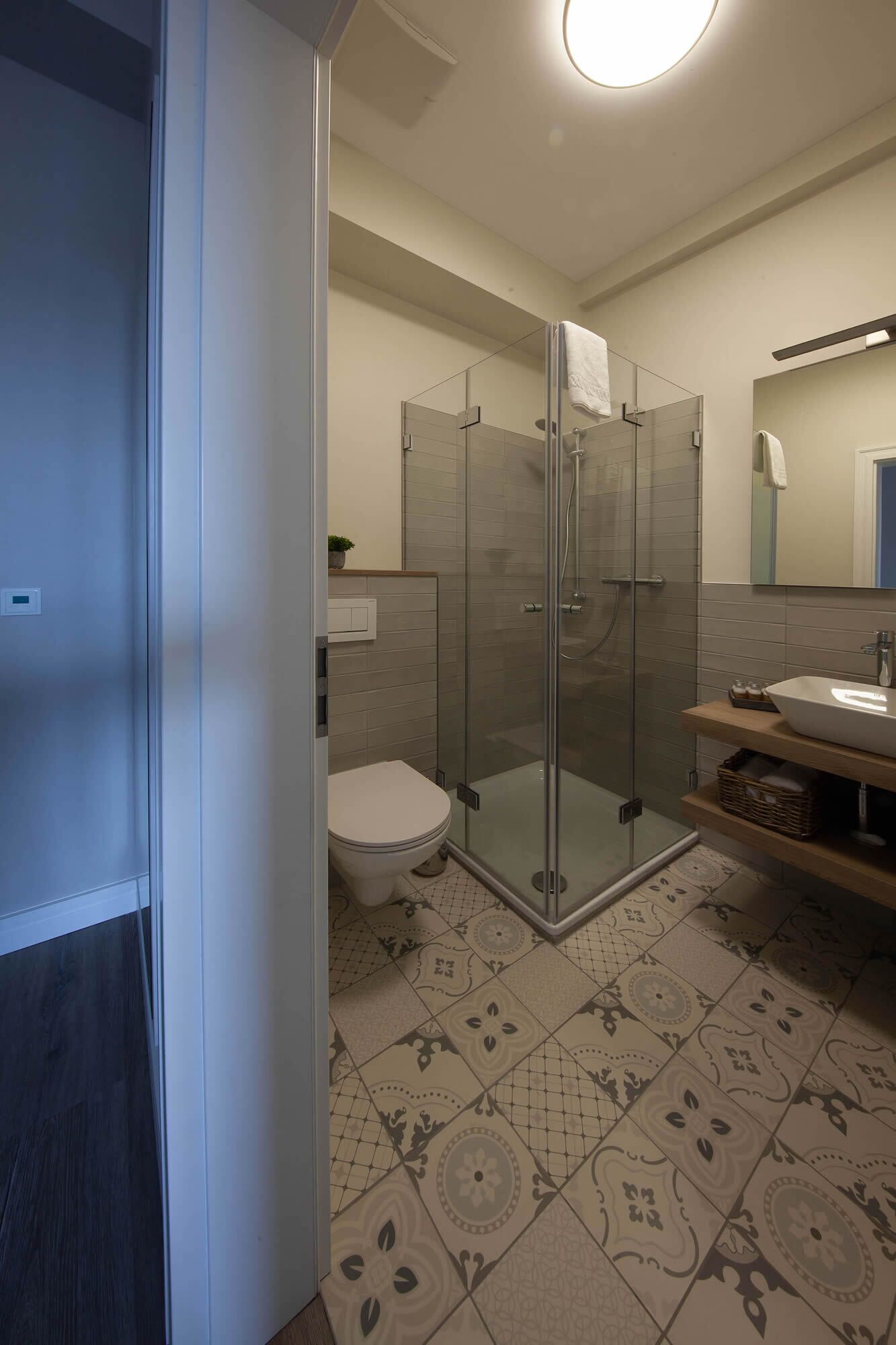 Een moderne badkamer met een douchecabine van glas, een wit toilet en een wastafel met spiegel.