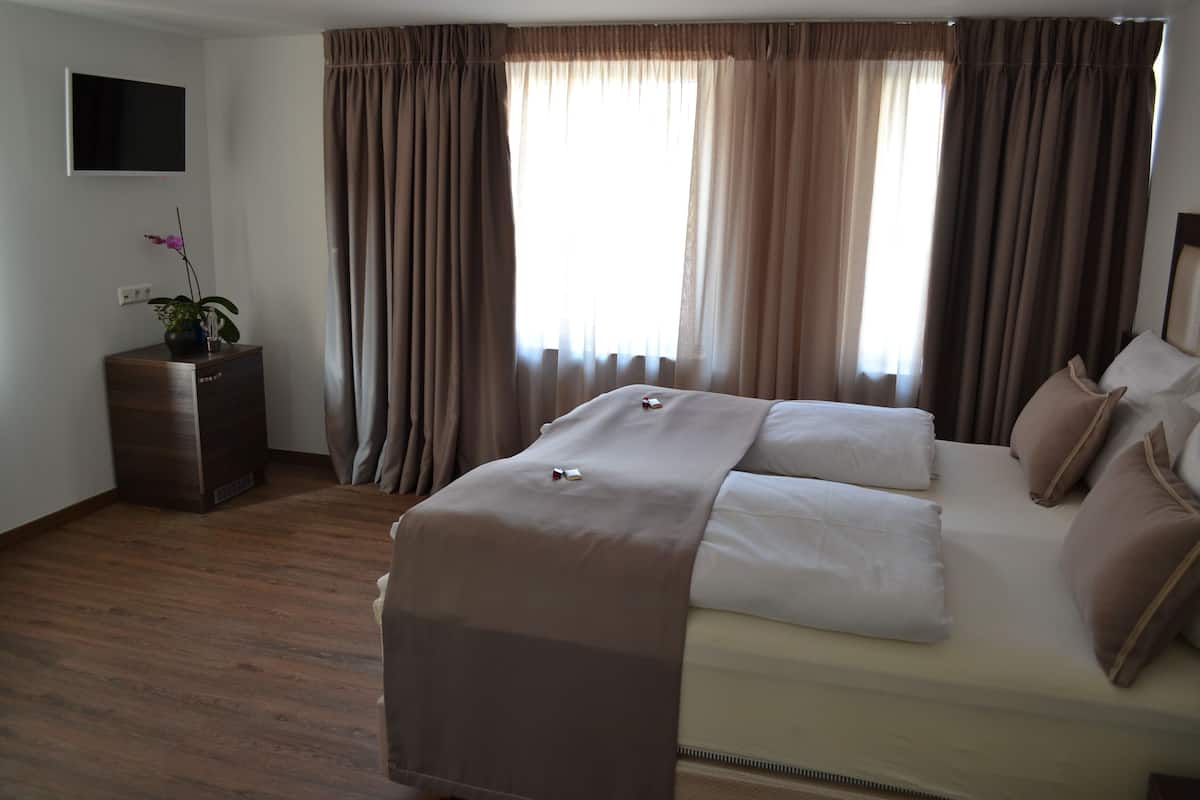 Una habitación de hotel con una cama, un televisor montado en la pared y una pequeña mesa con una planta.