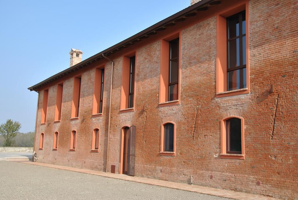 A long brick building with multiple windows and a chimney.