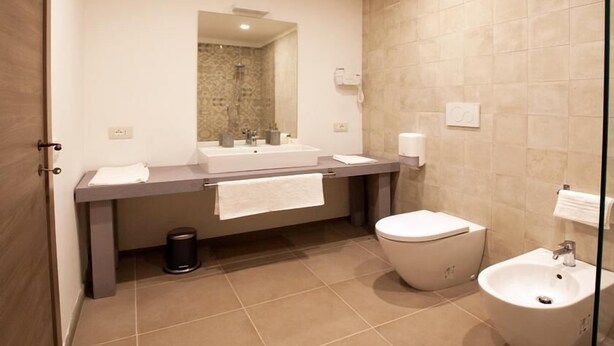 Un baño moderno con un espejo grande, dos lavamanos, un inodoro y un bidé.