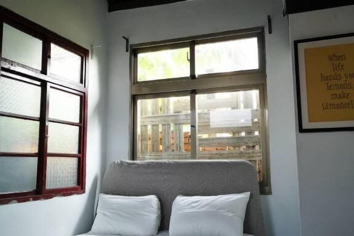 Ein Schlafzimmer mit Bett, Fenster und einer Wandleuchte.