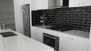 Uma cozinha moderna com frigorífico em aço inoxidável, fogão a gás e forno embutido.