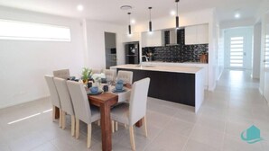 Uma cozinha moderna com ilha central, armários brancos e painel de fundo preto.
