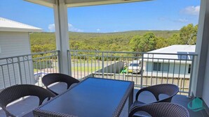 Varanda com móveis de vime e vista para uma paisagem verde.