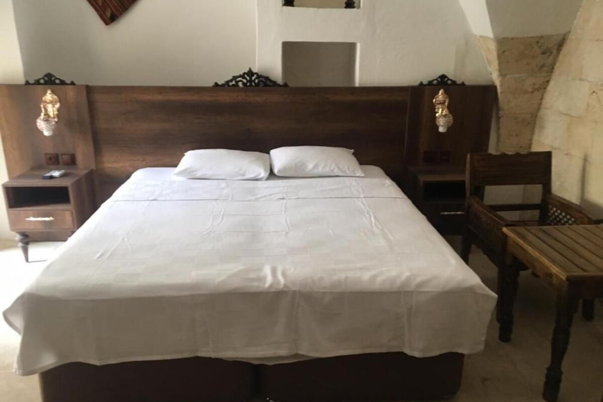 Quarto com uma cama grande, duas mesas de cabeceira, uma cadeira e um espelho na parede.