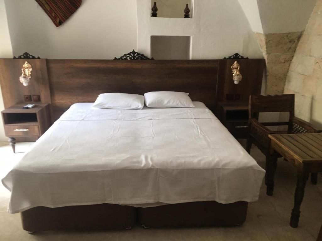 Ein Schlafzimmer mit einem großen Bett, zwei Nachttischen, einem Sessel und einem Spiegel an der Wand.