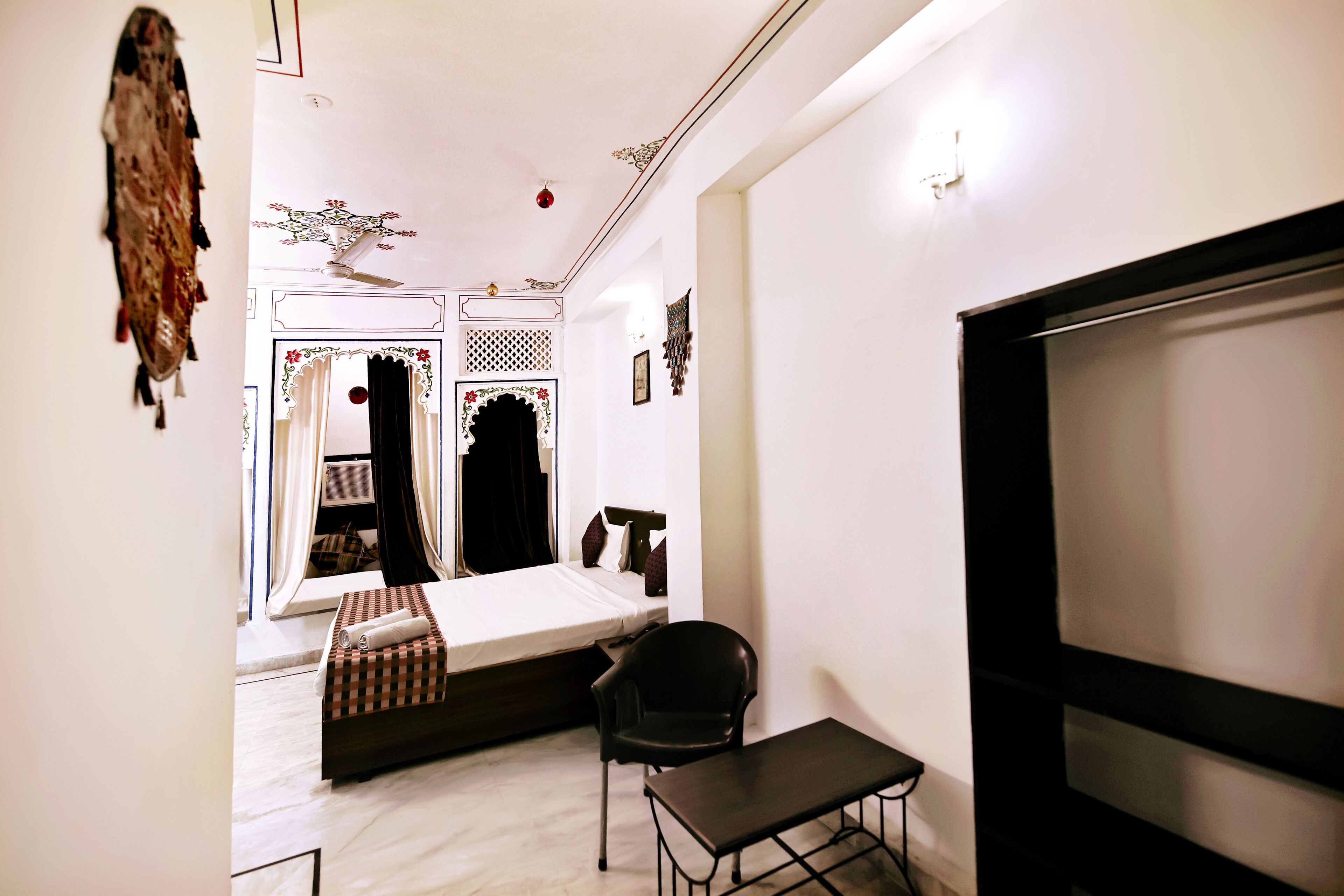 A bedroom with a bed, a chair, a small table, and a television.