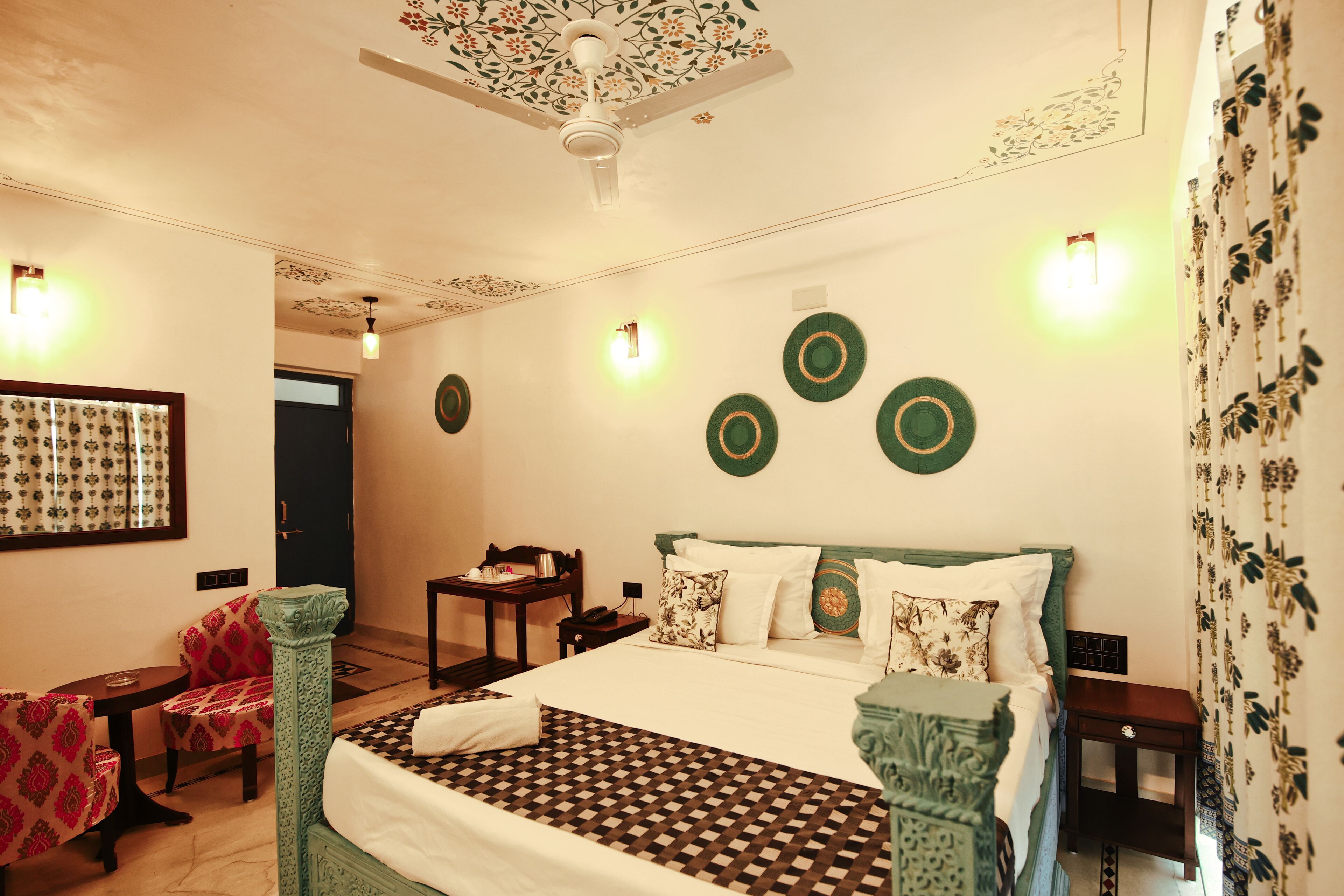 Ein Hotelzimmer mit Bett, Stuhl, Tisch und Deckenventilator.