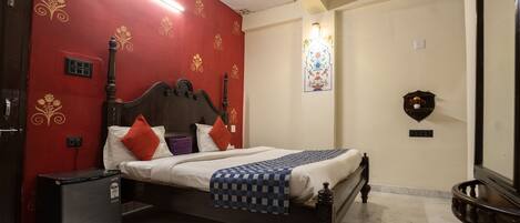 A bedroom with a bed, a nightstand, a heater, a wall-mounted clock, and a decorative mirror.