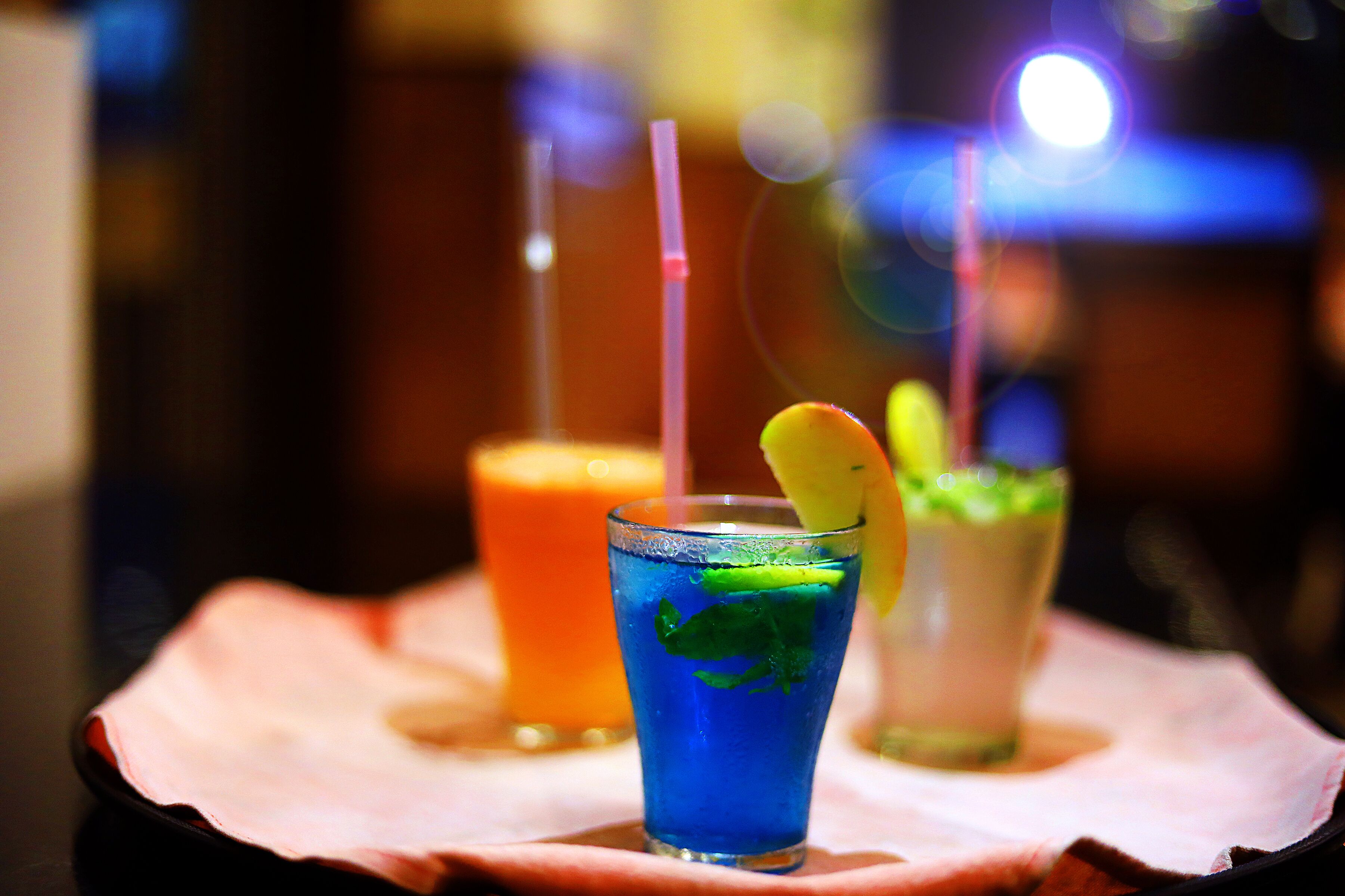 Three drinks on a table with straws.