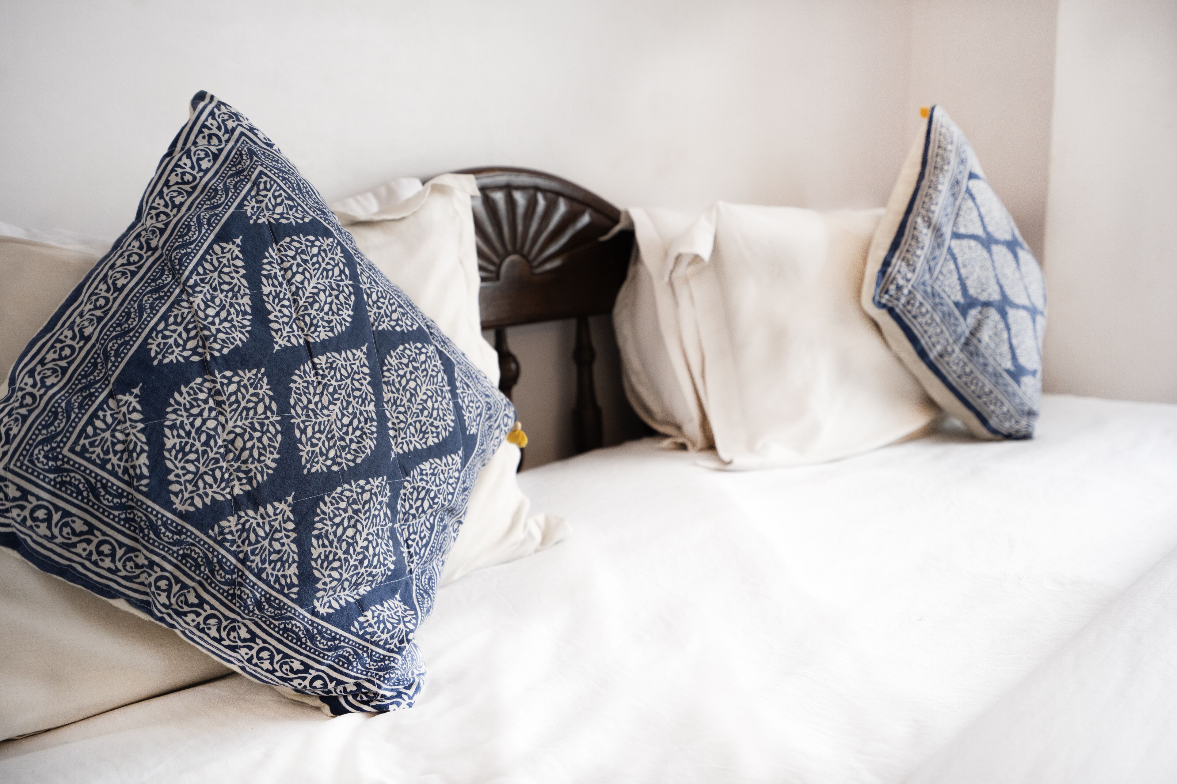 A bed with white bedding and two decorative pillows with a geometric pattern.