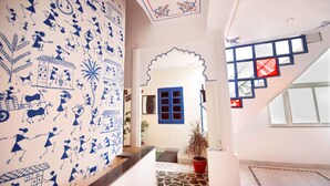 A hallway with a patterned wall, a blue-framed window, and a staircase with a geometric design. - The Lake View Hotel – On Lake Pichola (Udaipur)