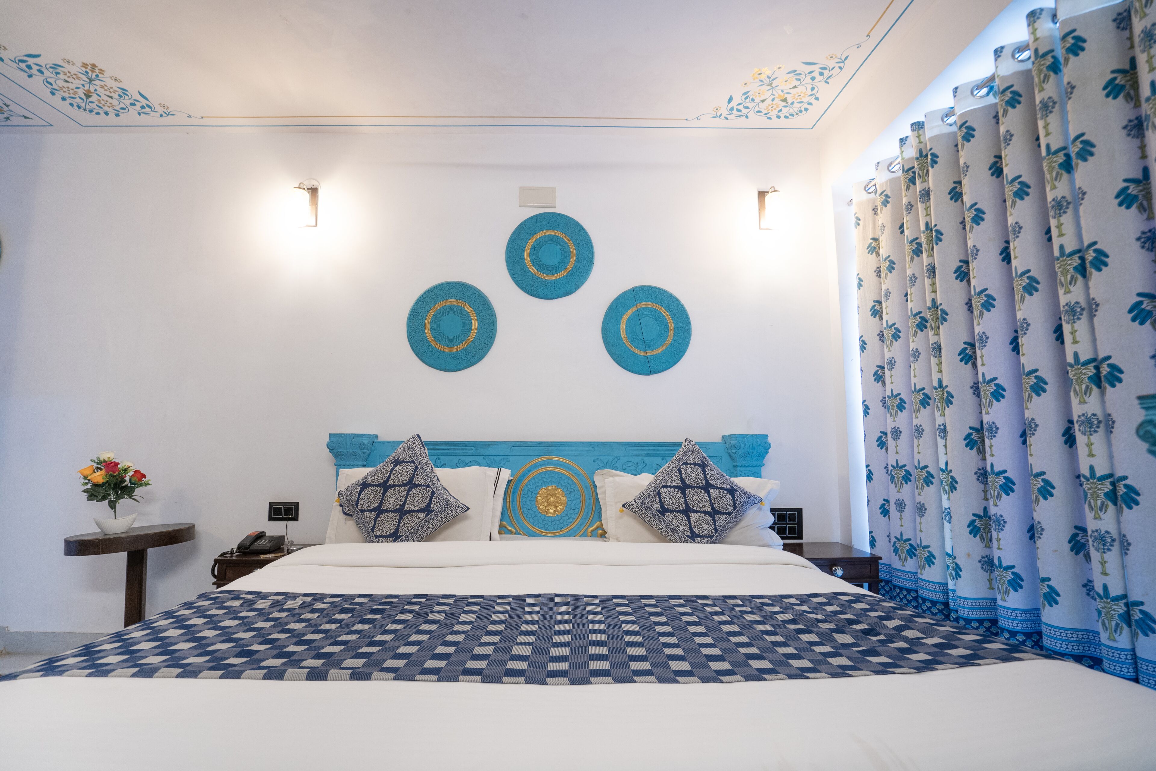 Un dormitorio con cama, mesita de noche, teléfono en la pared y decoración mural.
