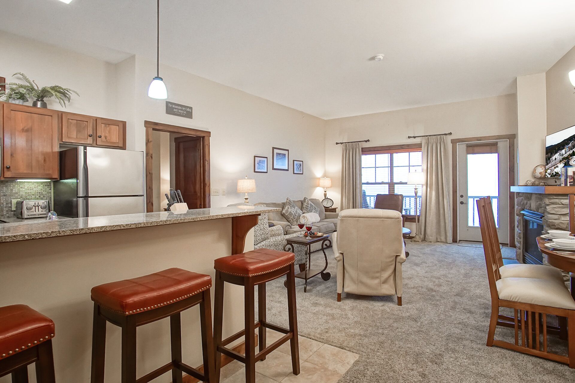 A spacious living area with a kitchen, bar stools, a sofa, and a dining table.