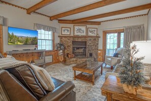 A cozy living room with a stone fireplace, leather sofa, and a television.