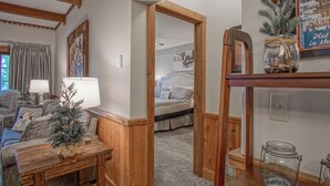 Een gezellige woonkamer met een houten plafond, een open haard, een bank, een salontafel en een kerstboom.