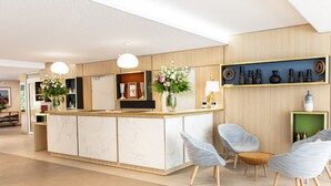A modern hotel lobby with a marble reception desk, light blue upholstered chairs, and a wooden wall with decorative shelves. - Residhome Toulouse Ponts Jumeaux (Toulouse)