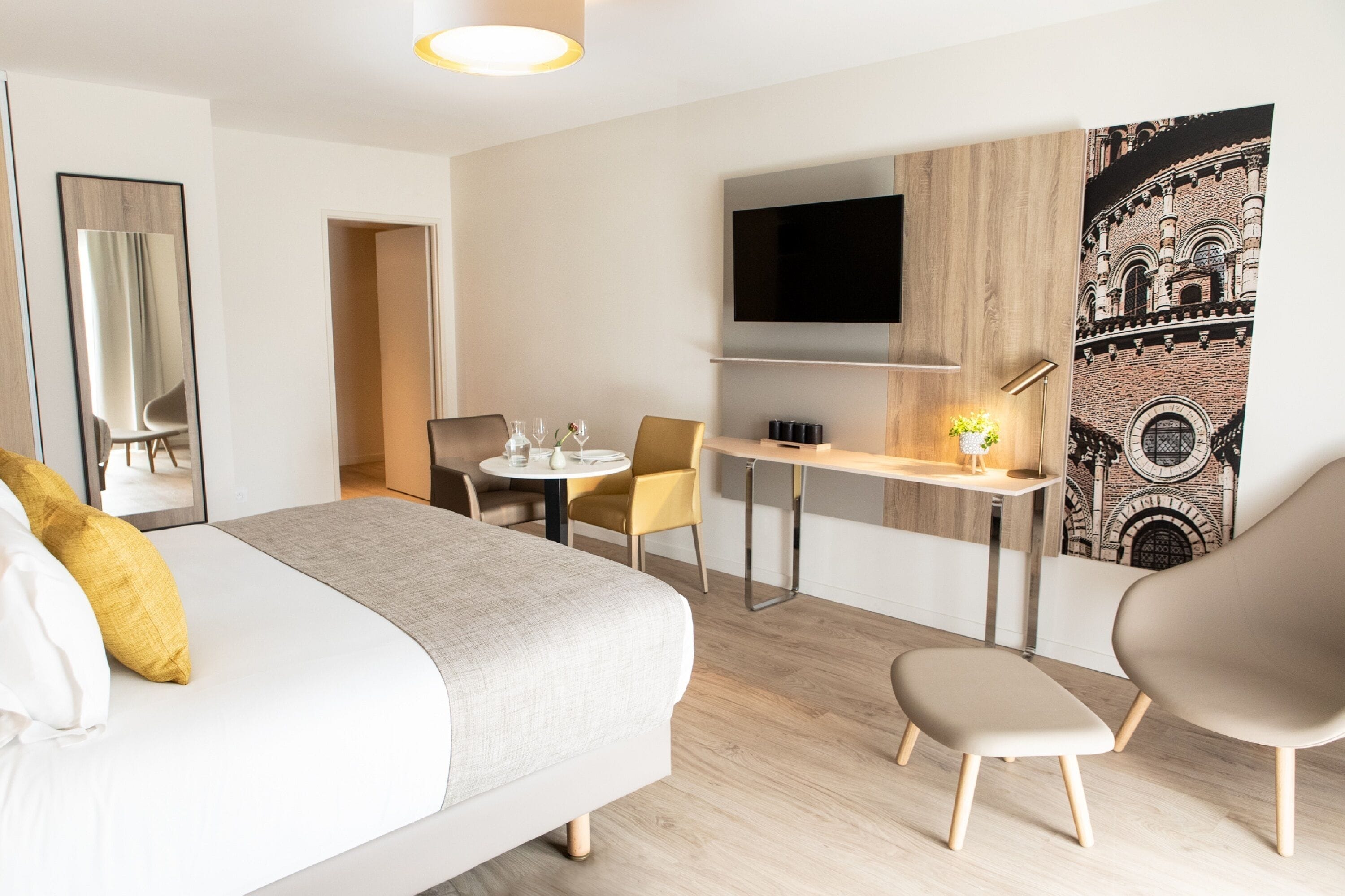 Une chambre d’hôtel moderne équipée d’un grand lit, d’un bureau, d’une chaise, d’une télévision et d’une œuvre d’art accrochée au mur.