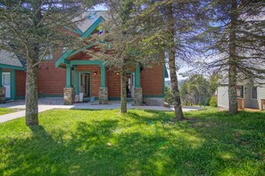 A wooden cabin with a porch, stone pillars, and a well-maintained lawn. - Camp 4 #1 3 bedroom, 3.5 bath (Snowshoe)