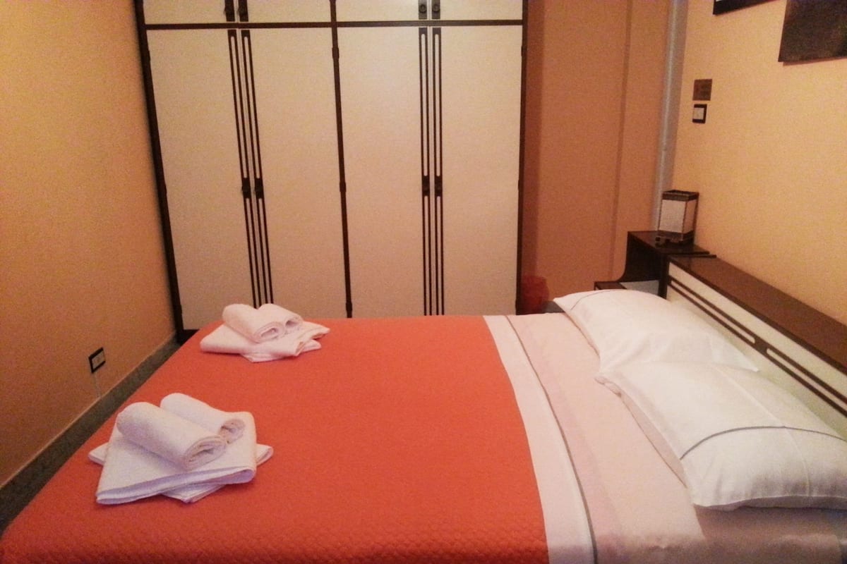 A hotel room with a bed, a nightstand, and a wardrobe.