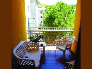 A balcony with two white wicker chairs, a small table, and a potted plant. - B&B Night & Day (Cosenza)