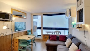 Una sala de estar moderna con un sofá, una mesa de comedor y un televisor montado en la pared.