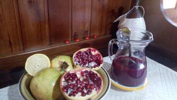 A plate with a pomegranate and a lemon, and a glass pitcher with a dark liquid.