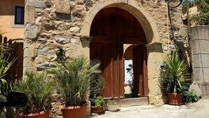 A stone building with an arched entrance, potted plants, and a street lamp.