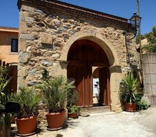 Un edificio de piedra con una entrada arqueada, plantas en macetas y un farol.