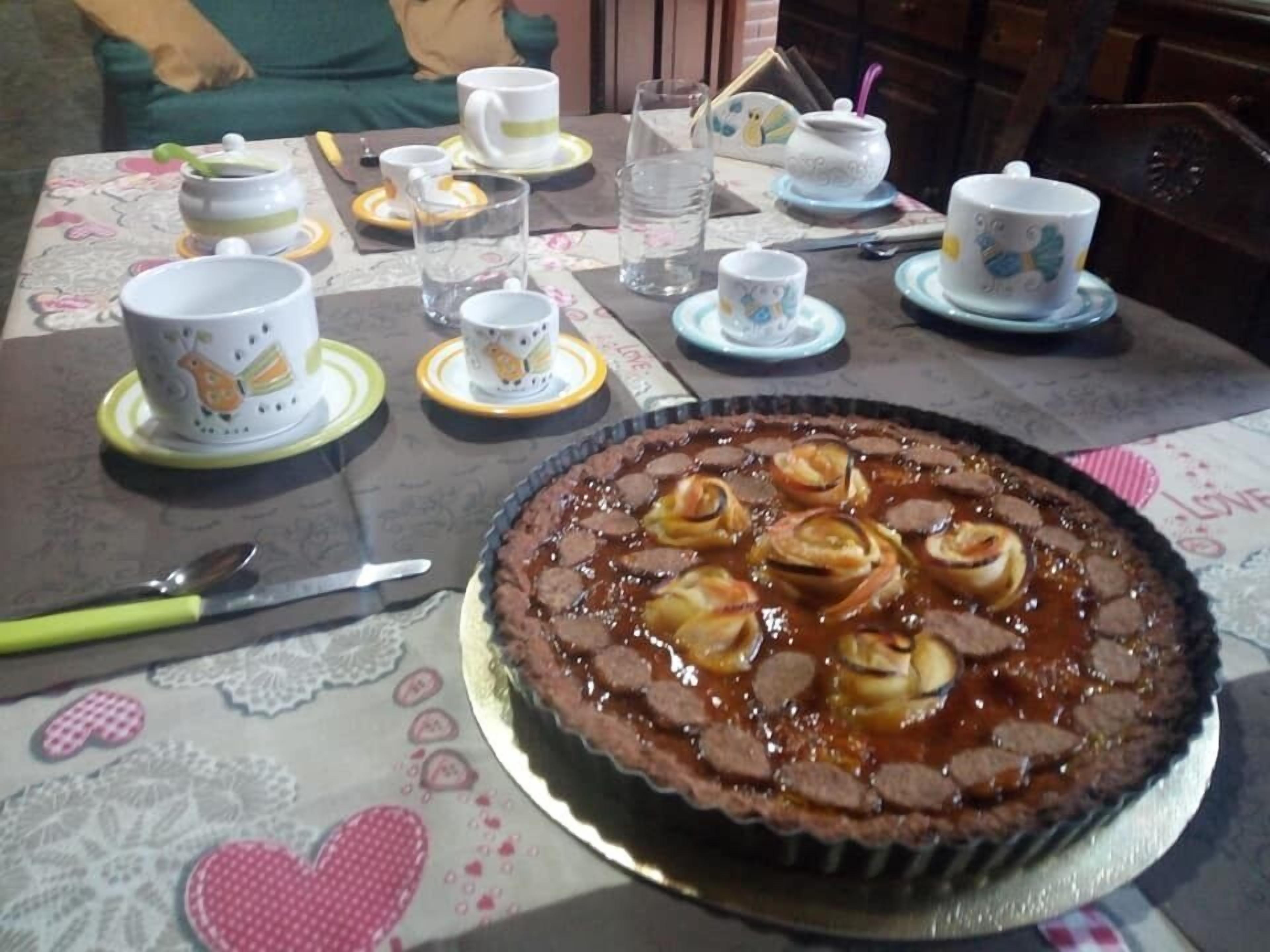 Een eettafel met een chocoladetaart, theekoppen en een mes.