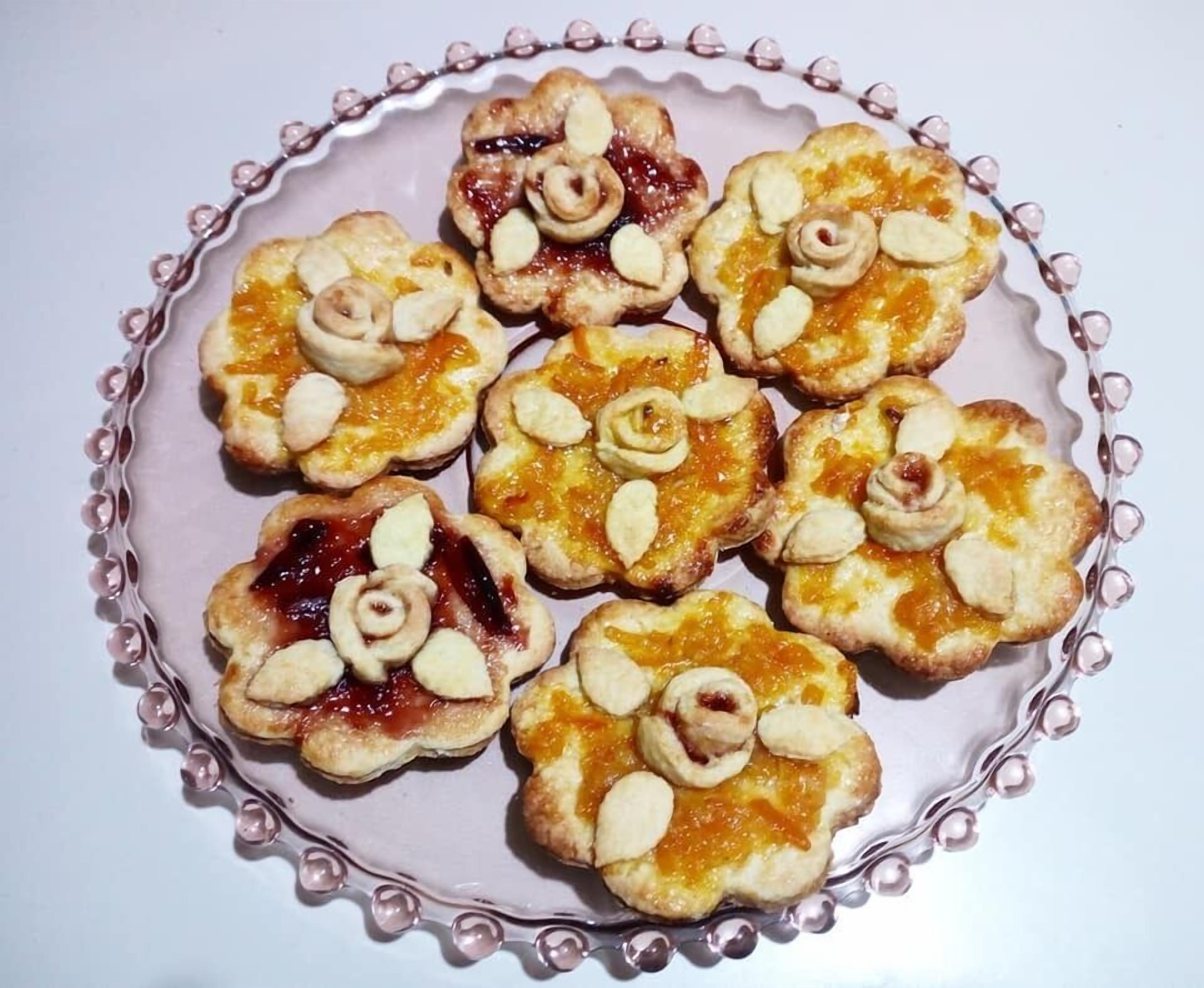 Une assiette remplie de petites pâtisseries à bords décoratifs, disposées sur une table.