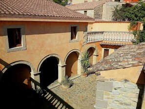 Un patio con suelo de piedra, puertas arqueadas y techo de tejas.