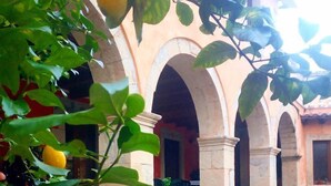 A courtyard with a lemon tree, stone arches, and a tiled floor.