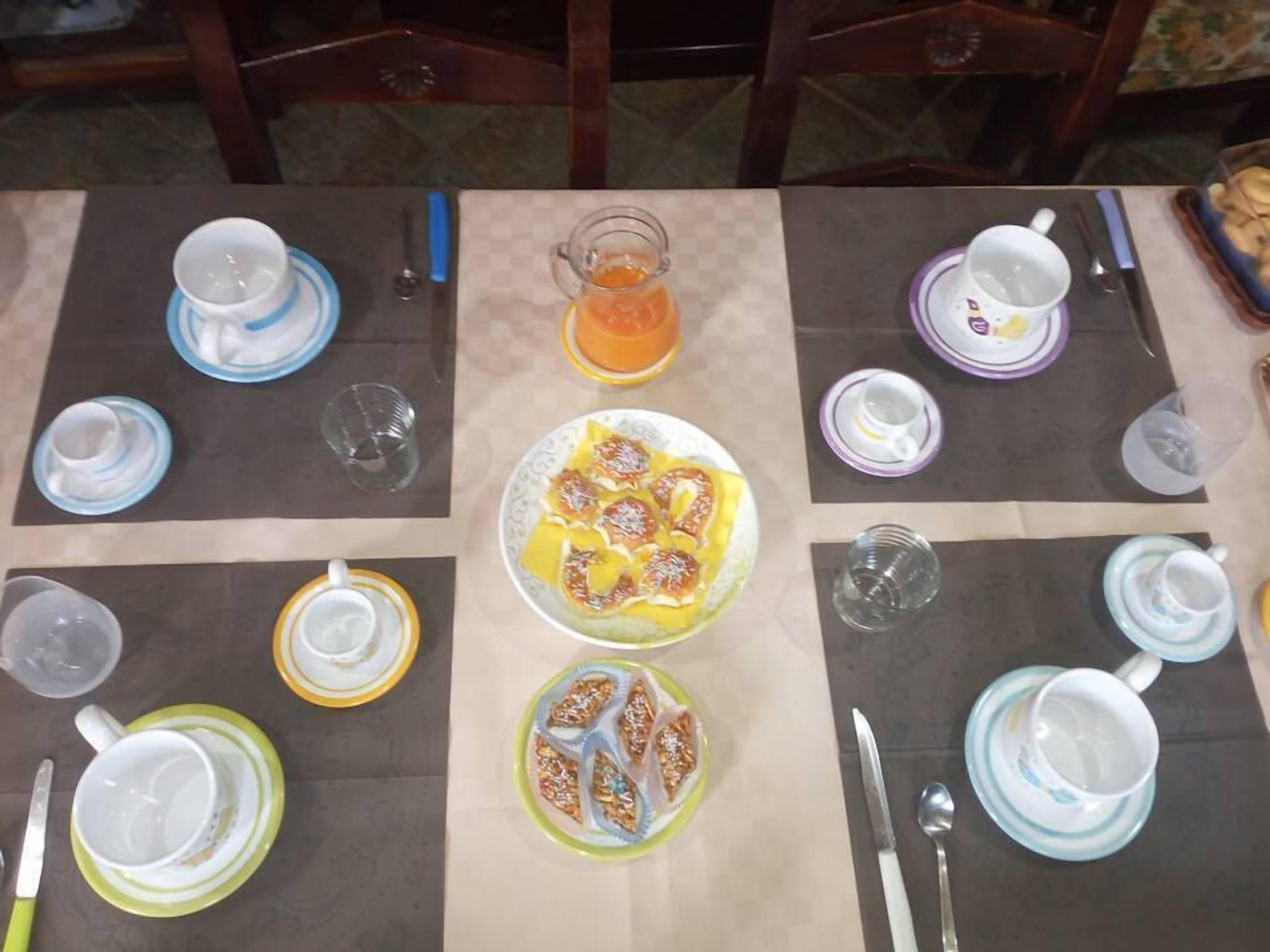 A dining table set with plates, cups, and cutlery, arranged for a meal.