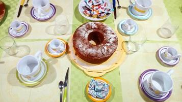 Una mesa dispuesta para una comida, con un pastel central, varias tazas y platitos, y un pequeño recipiente con salsas.