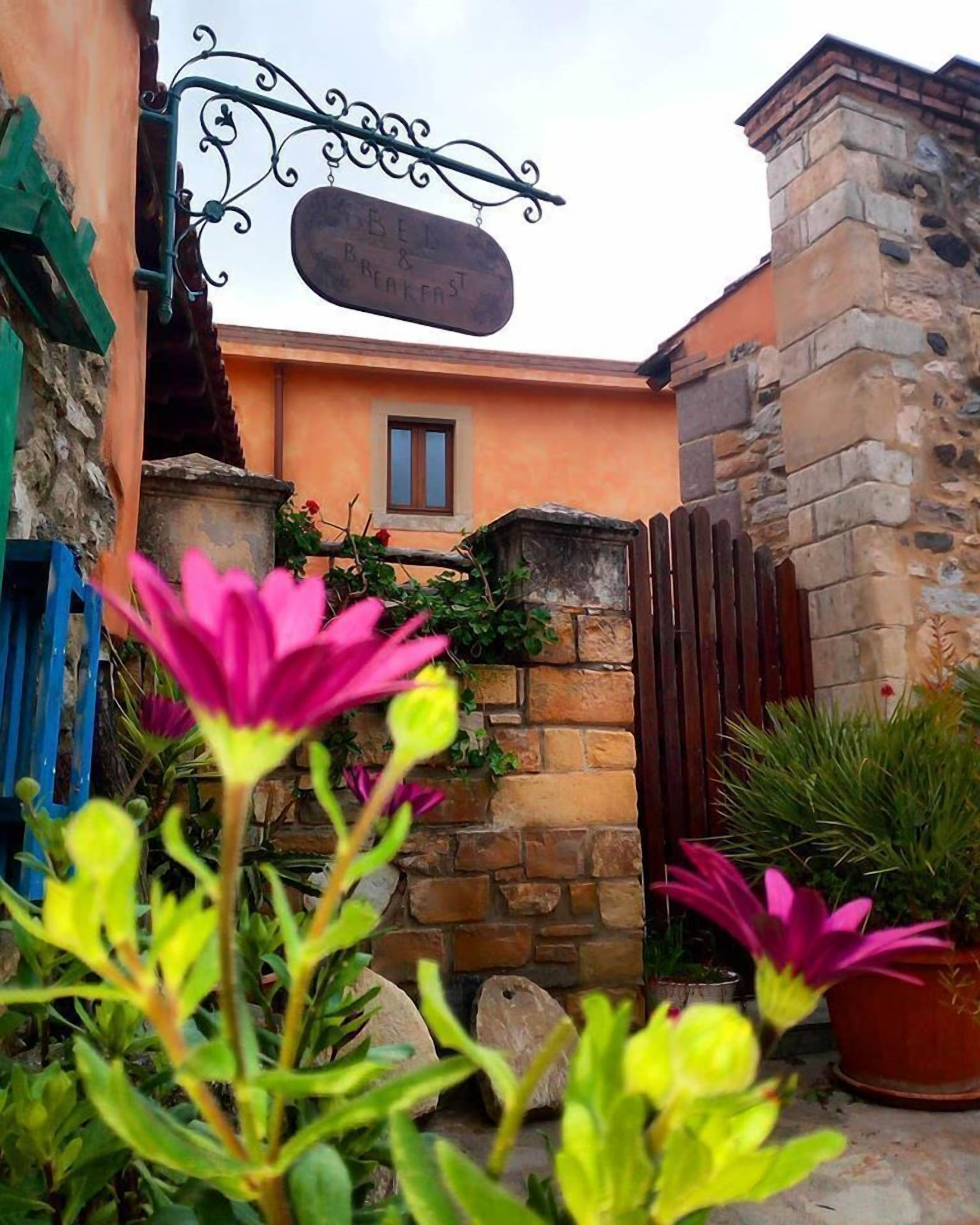 Un edificio rustico con un muro in pietra e un cancello di legno.