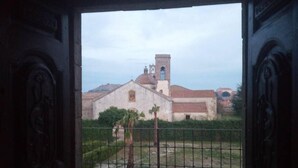An entrance with a view of a church with a bell tower and a fence in front.