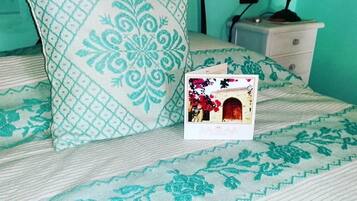 Una cama con ropa de cama estampada, una almohada, una mesita de noche con lámpara y un pequeño marco de fotos.