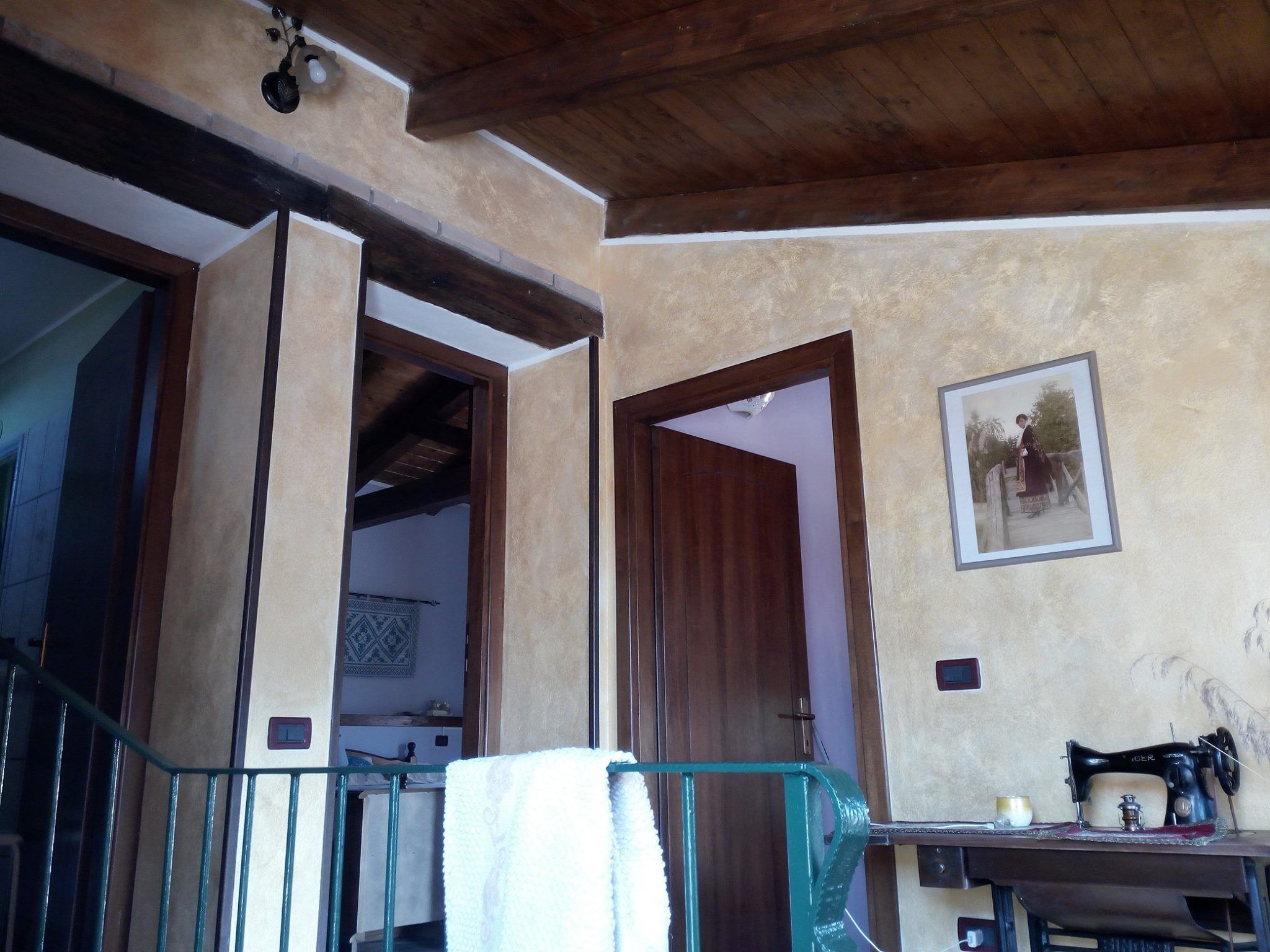Una habitación con techo de madera, una máquina de coser sobre una mesa y un cuadro en la pared.