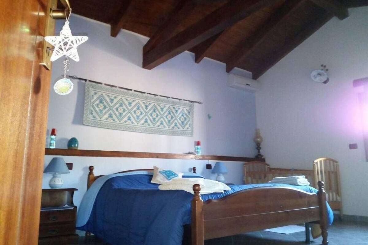 A bedroom with a wooden bed, a nightstand, a lamp, and a wall hanging.