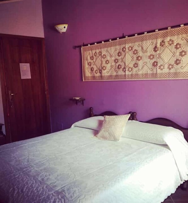 Una habitación con una cama, una puerta de madera y un adorno en la pared.