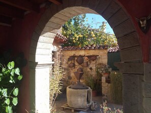 Un arco de piedra al aire libre con un muro de piedra rústico, una maceta de barro grande y plantas en macetas.