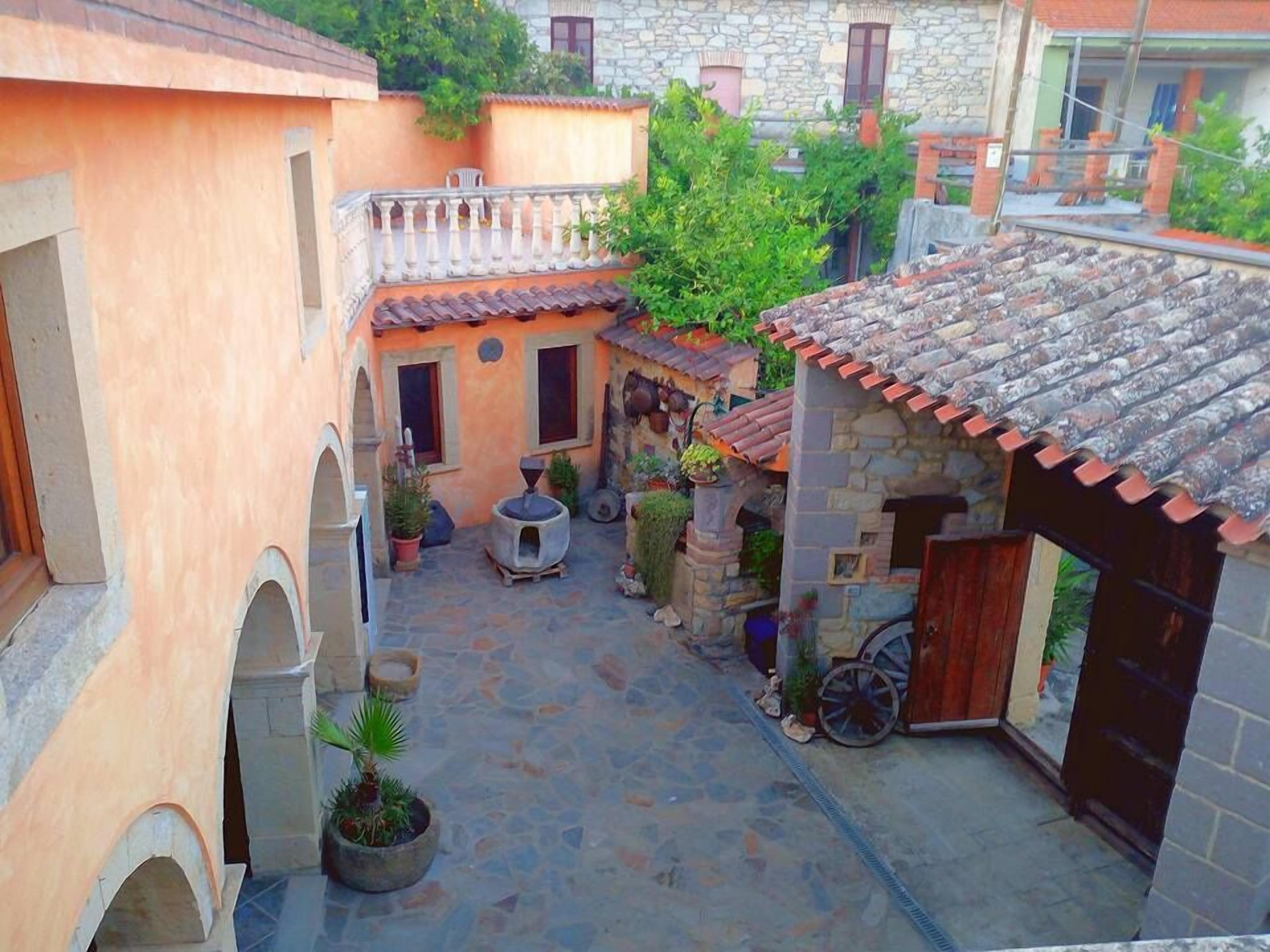 A courtyard with stone walls, a tiled roof, and potted plants.
