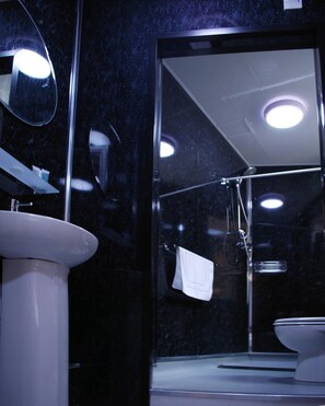 A bathroom with a glass shower enclosure, a white sink, and a mirror. - The Liverpool Inn Hotel (Liverpool)
