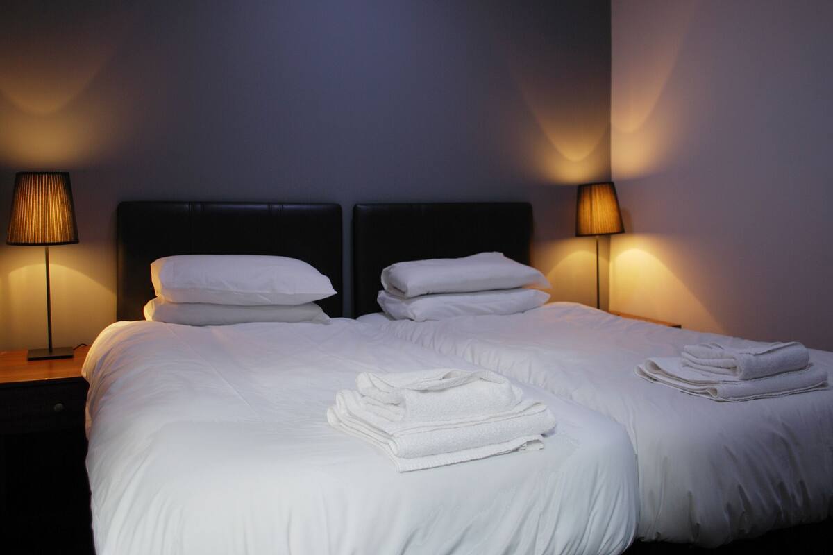 A hotel room with a large bed, two bedside tables, and two lamps.