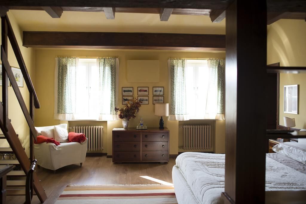 A bedroom with a bed, a dresser, a chair, and a radiator.