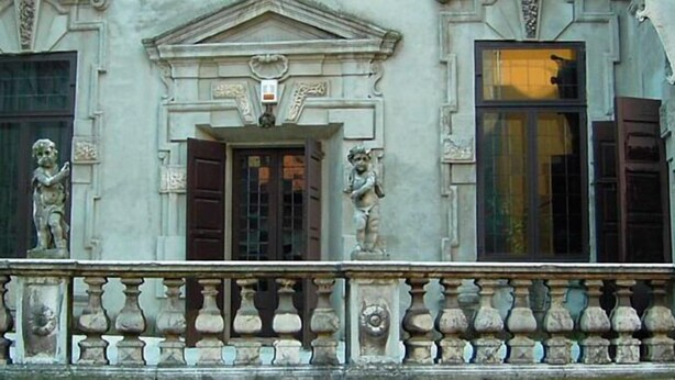 A building facade with classical architectural elements, including statues and a balustrade.
